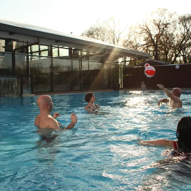 zwei Frauen und zwei Männer spielen im Aussenbecken Wasserball