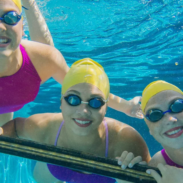 drei junge Frauen schauen unter Wasser durch einen Bilderrahmen